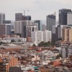 Vista aérea panorâmica de Barcelona, com edifícios residenciais e arranha-céus formando a paisagem urbana.