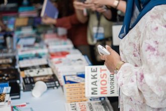 Livros expostos em uma feira literária, enquanto visitantes observam as publicações.