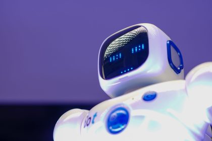Robô humanoide moderno com rosto digital iluminado diante de uma tela tecnológica.