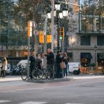 Ciclistas e pedestres aguardam a abertura do semáforo em um cruzamento movimentado de Barcelona.