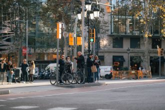 Ciclistas e pedestres aguardam a abertura do semáforo em um cruzamento movimentado de Barcelona.