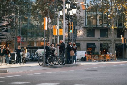Ciclistas e pedestres aguardam a abertura do semáforo em um cruzamento movimentado de Barcelona.