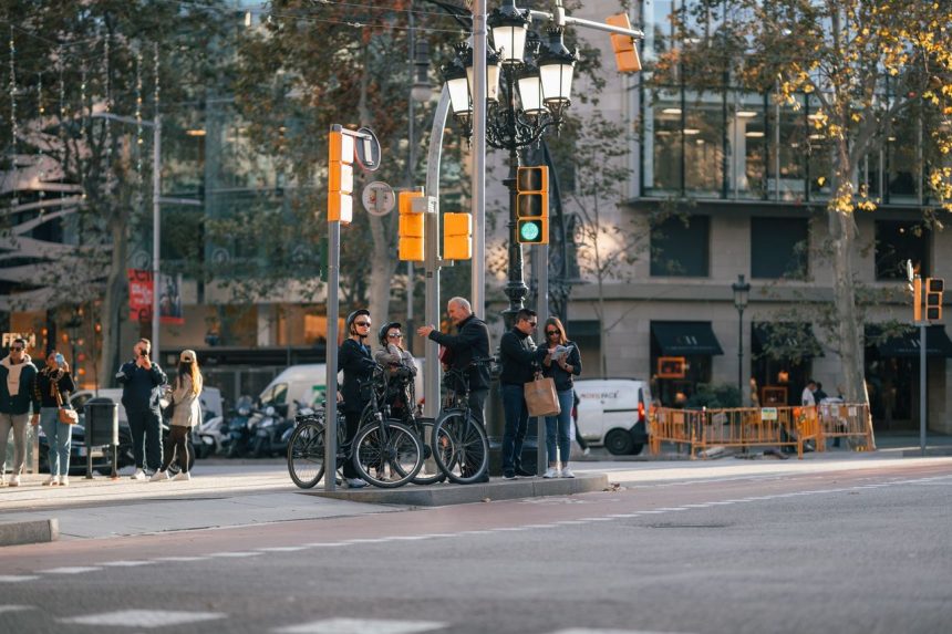 Ciclistas e pedestres aguardam a abertura do semáforo em um cruzamento movimentado de Barcelona.