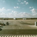 Vista de um terminal aeroportuário e da pista, com várias aeronaves sob um céu nublado.