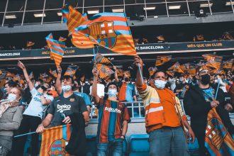 Torcedores do FC Barcelona acenam com bandeiras durante uma partida de futebol.