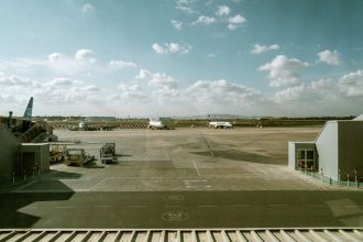 Vista de um terminal aeroportuário e da pista, com várias aeronaves sob um céu nublado.