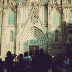 Pessoas diante da entrada de uma catedral gótica em Barcelona.