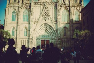 Pessoas diante da entrada de uma catedral gótica em Barcelona.