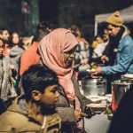Pessoas reunidas em um evento comunitário ao ar livre no bairro do Raval, em Barcelona.