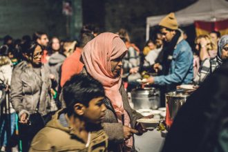 Pessoas reunidas em um evento comunitário ao ar livre no bairro do Raval, em Barcelona.